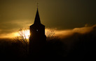 Silhouet van de kerktoren van Hoogeloon bij zonsondergang.